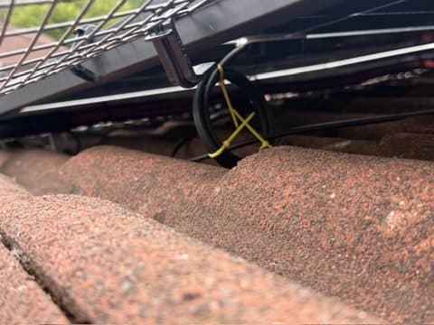 Cabling resting on tiles, held with a non-UV-rated tie.